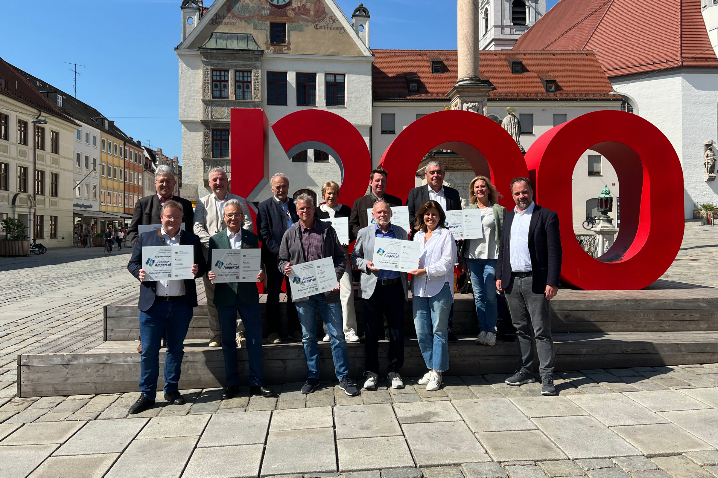 Bürgermeister mit Förderhinweis vor Freisinger Rathaus